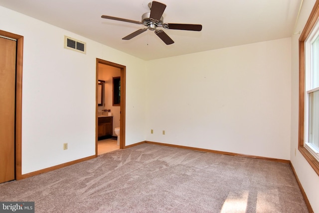 unfurnished bedroom with light carpet, ensuite bath, visible vents, and baseboards