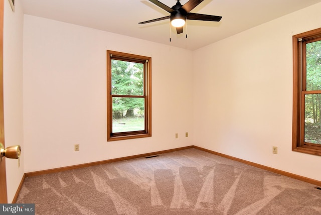 carpeted empty room featuring ceiling fan and a healthy amount of sunlight