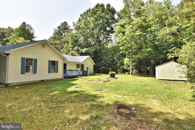 view of yard with an outbuilding, a shed, central AC unit, and a wooden deck