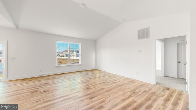 empty room with light hardwood / wood-style flooring and vaulted ceiling