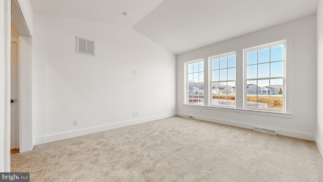 spare room featuring light carpet and vaulted ceiling