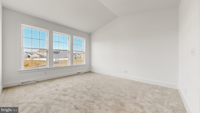 spare room featuring carpet flooring and vaulted ceiling