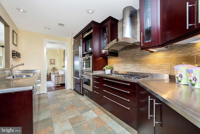 kitchen featuring appliances with stainless steel finishes, stainless steel counters, tasteful backsplash, wall chimney exhaust hood, and sink