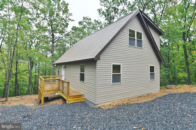 view of side of property featuring a deck and a shingled roof