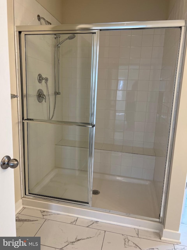 bathroom featuring marble finish floor and a stall shower