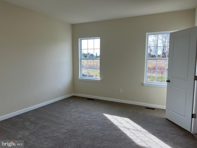 unfurnished room featuring plenty of natural light, visible vents, and baseboards