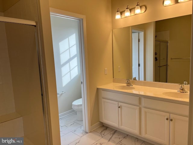 bathroom featuring marble finish floor, a sink, a shower stall, and baseboards