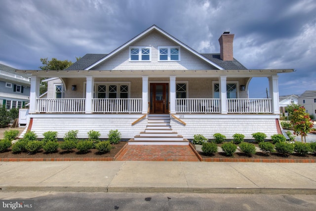 view of front of home featuring covered porch and a chimney