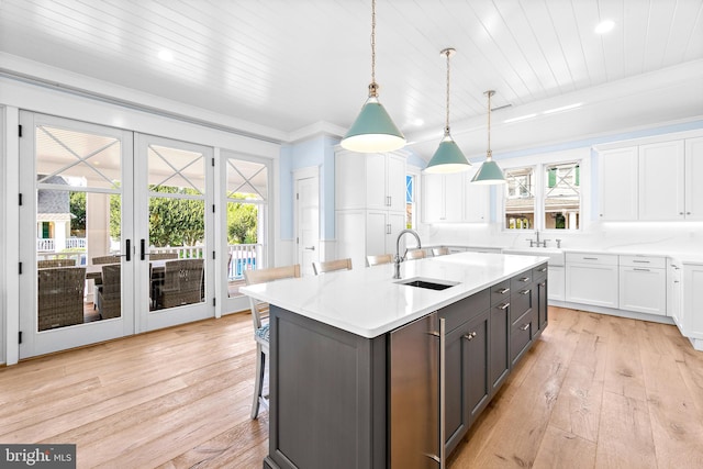 kitchen featuring light hardwood / wood-style flooring, white cabinetry, french doors, sink, and a center island with sink