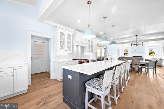 kitchen with hanging light fixtures, white cabinetry, and glass insert cabinets