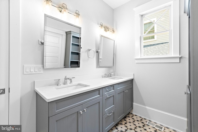 bathroom with double vanity, baseboards, visible vents, and a sink