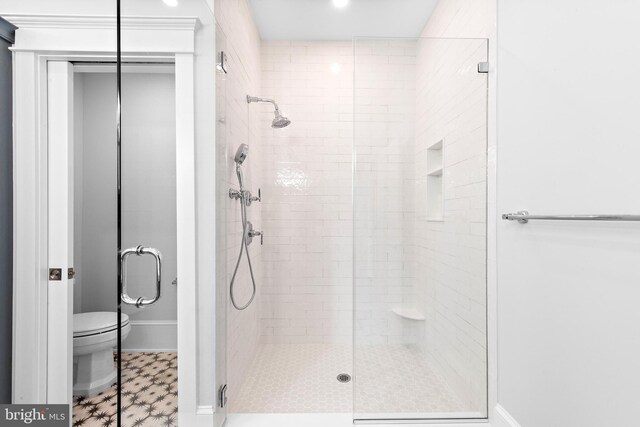 bathroom featuring a shower with shower door, toilet, and tile patterned floors