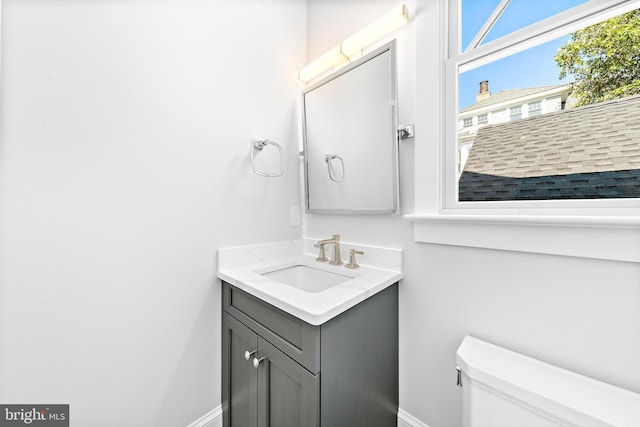 bathroom featuring toilet, vanity, and baseboards