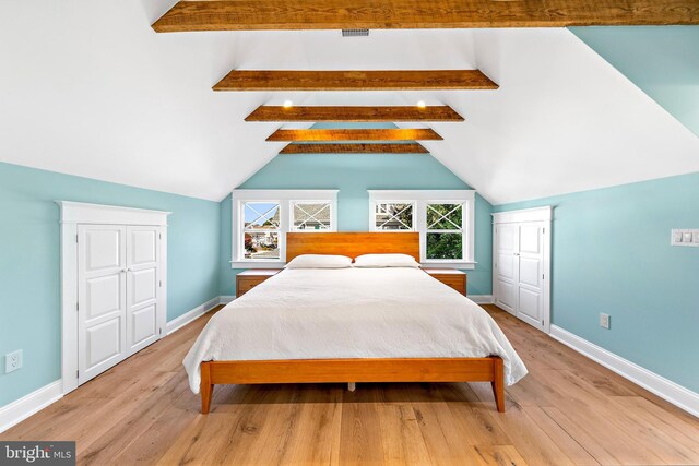 bedroom with light wood-type flooring and lofted ceiling with beams