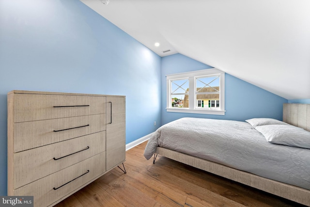 bedroom featuring lofted ceiling, visible vents, light wood-style flooring, and baseboards