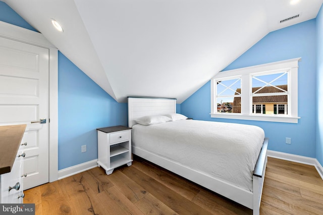 bedroom with lofted ceiling, wood finished floors, visible vents, and baseboards