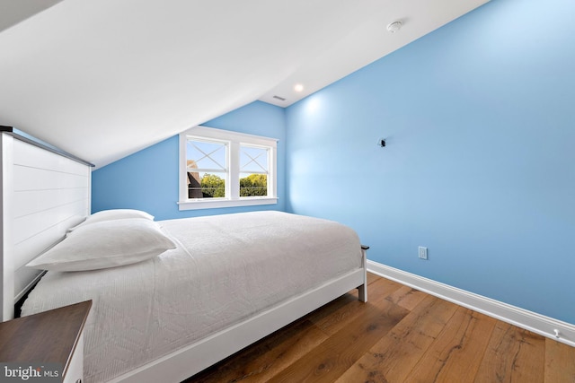 bedroom featuring lofted ceiling, dark wood-type flooring, and baseboards