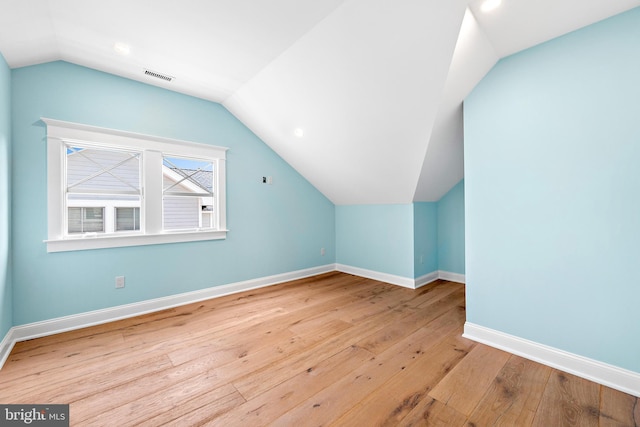 bonus room featuring light wood-style floors, baseboards, visible vents, and vaulted ceiling