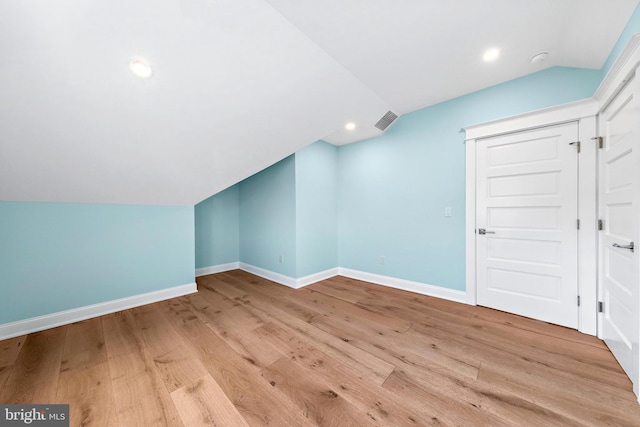 additional living space with light wood-type flooring and vaulted ceiling