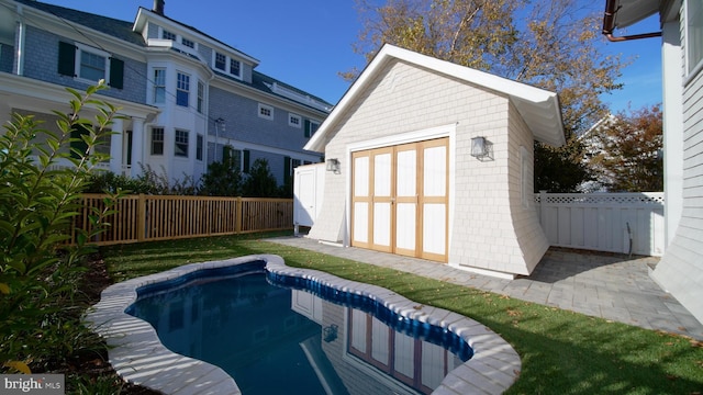 view of swimming pool with a fenced in pool, an outbuilding, a fenced backyard, and a storage unit