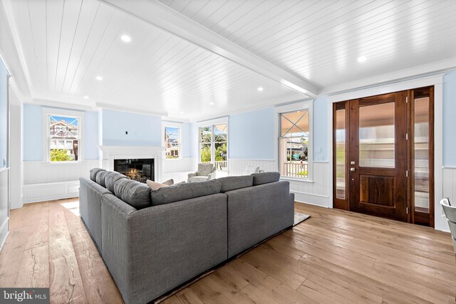 living room featuring light hardwood / wood-style flooring, ornamental molding, and beamed ceiling