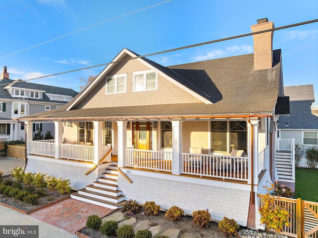 view of front of property featuring a chimney, a porch, and roof with shingles