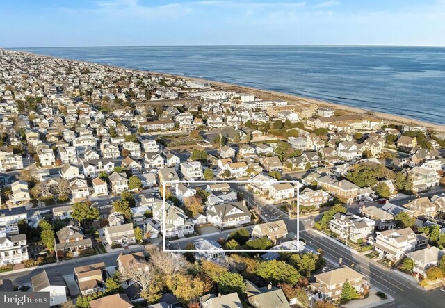 drone / aerial view with a residential view, a water view, and a beach view