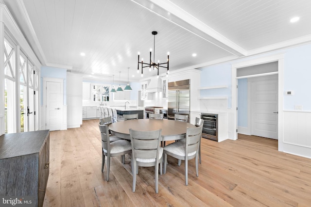 dining area featuring ornamental molding, wine cooler, light wood-style flooring, and a healthy amount of sunlight