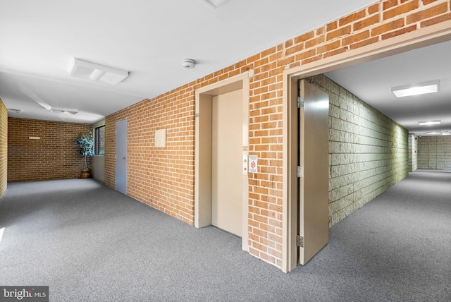 corridor featuring carpet floors, elevator, and brick wall