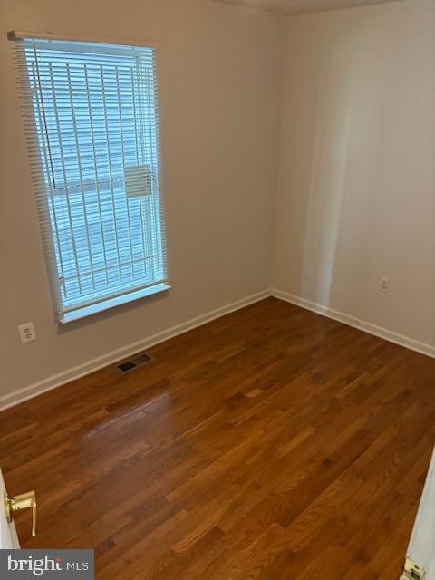 unfurnished room featuring dark wood-type flooring and a healthy amount of sunlight