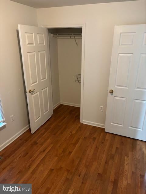 unfurnished bedroom with a closet and dark hardwood / wood-style flooring