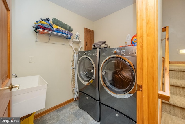 clothes washing area featuring sink, a textured ceiling, and independent washer and dryer