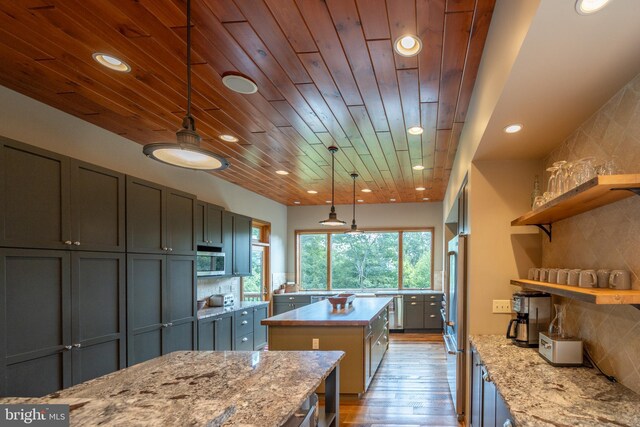 kitchen with light stone countertops, light hardwood / wood-style flooring, pendant lighting, wood ceiling, and appliances with stainless steel finishes