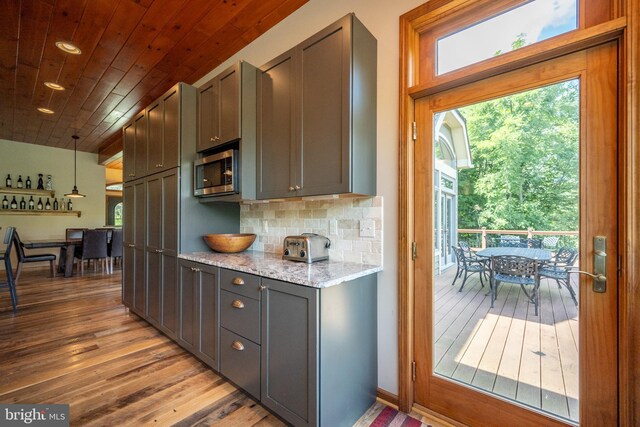 kitchen with decorative backsplash, light stone counters, decorative light fixtures, wooden ceiling, and hardwood / wood-style floors