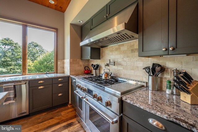 kitchen featuring dark hardwood / wood-style flooring, light stone counters, appliances with stainless steel finishes, and tasteful backsplash