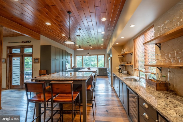 kitchen with light stone counters, sink, pendant lighting, and hardwood / wood-style flooring