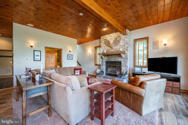 living room featuring beam ceiling, a stone fireplace, wood ceiling, and wood-type flooring