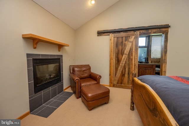 bedroom with dark carpet, a barn door, a tile fireplace, and vaulted ceiling