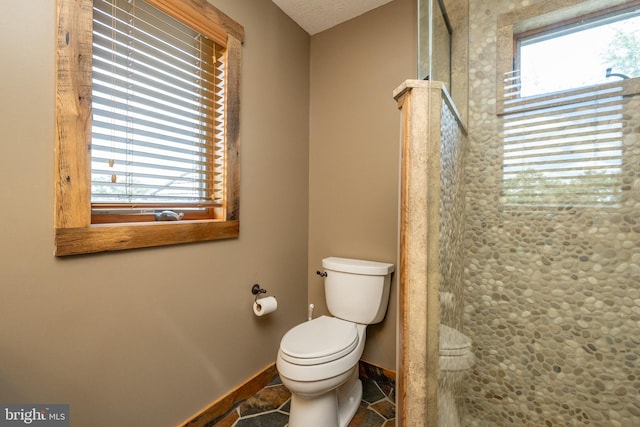 bathroom featuring a textured ceiling, plenty of natural light, toilet, and walk in shower