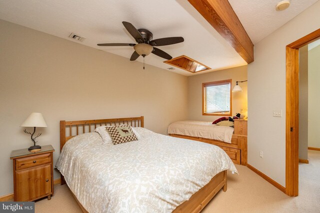 bedroom featuring beam ceiling, ceiling fan, light carpet, and a textured ceiling