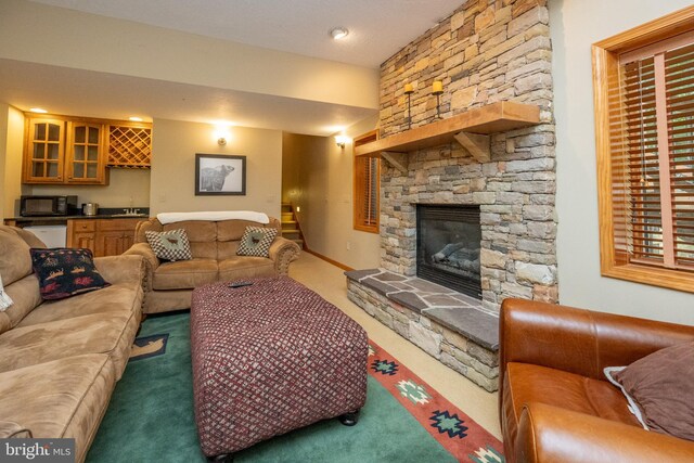 living room featuring dark colored carpet, bar, and a fireplace