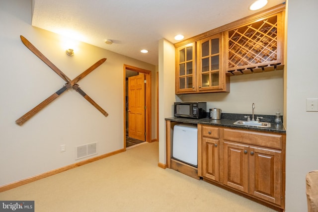 kitchen with a textured ceiling, light colored carpet, sink, and white dishwasher