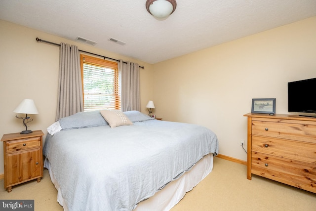 bedroom featuring light carpet and a textured ceiling