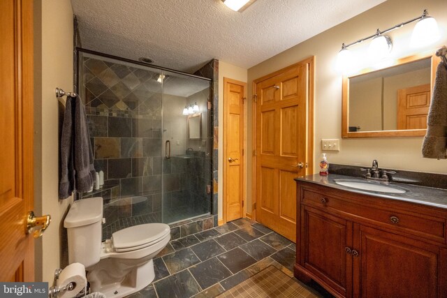 bathroom featuring vanity, toilet, an enclosed shower, and a textured ceiling