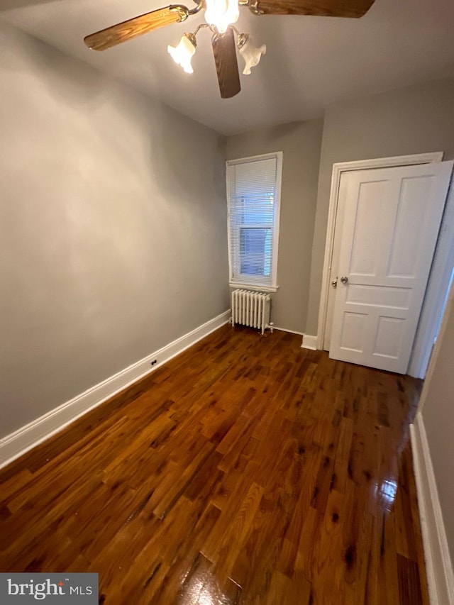 unfurnished bedroom with radiator, ceiling fan, and dark hardwood / wood-style flooring