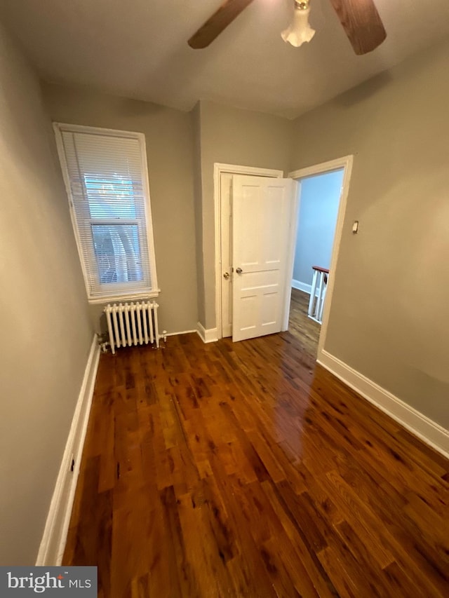 interior space featuring radiator heating unit, dark wood-type flooring, ceiling fan, and a closet