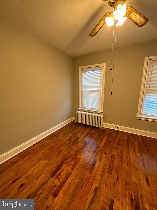 spare room featuring radiator heating unit, dark wood-type flooring, and ceiling fan