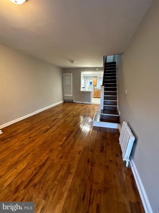 unfurnished living room with dark wood-type flooring and radiator heating unit