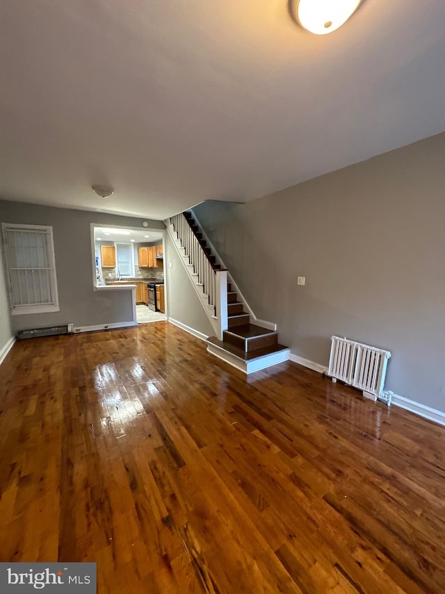 unfurnished living room featuring hardwood / wood-style floors and radiator heating unit