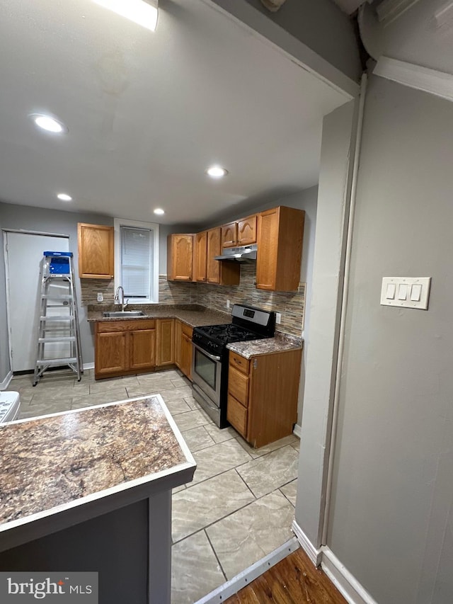 kitchen with light hardwood / wood-style floors, sink, backsplash, and stainless steel gas range oven